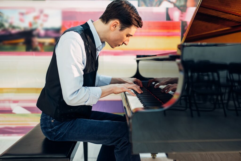 male-pianist-practicing-composition-on-grand-piano