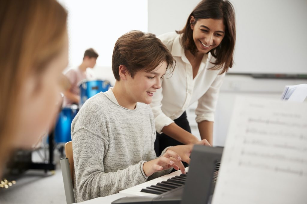 male-pupil-with-teacher-playing-piano-in-music-lesson