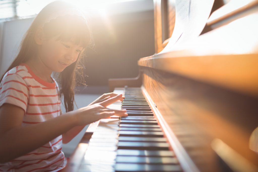 smiling-girl-practicing-piano-in-classroom